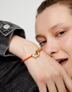 Pulsera de cuero naranja con mosquetón entrelazado en oro