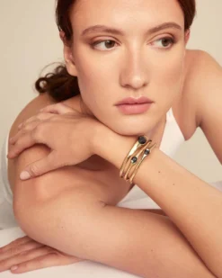 Pulsera rígida bañada en oro 18k con 2 cristales grises, 1 blanco y 1 rosa